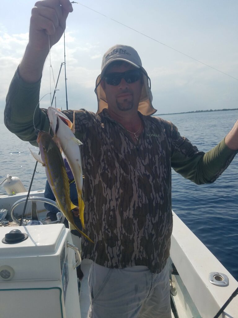 "A successful fisherman holding up a fresh catch while wearing a protective sun hat on the boat."
