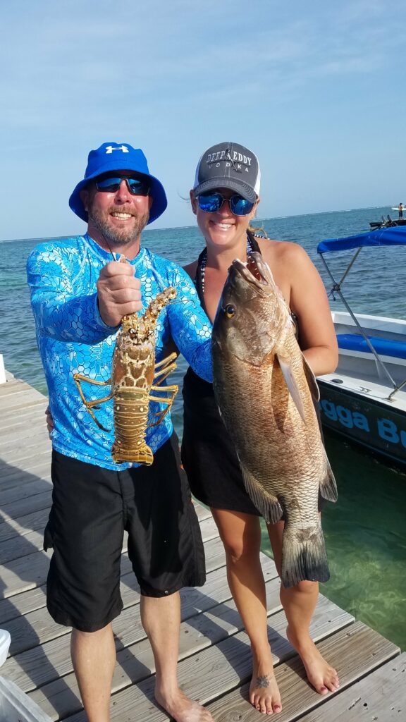 "Happy couple displaying a large lobster and snapper caught during their private reef tour."