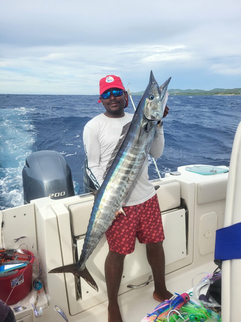 "Professional fishing guide holding a large Wahoo on a private boat charter in San Pedro, Belize."