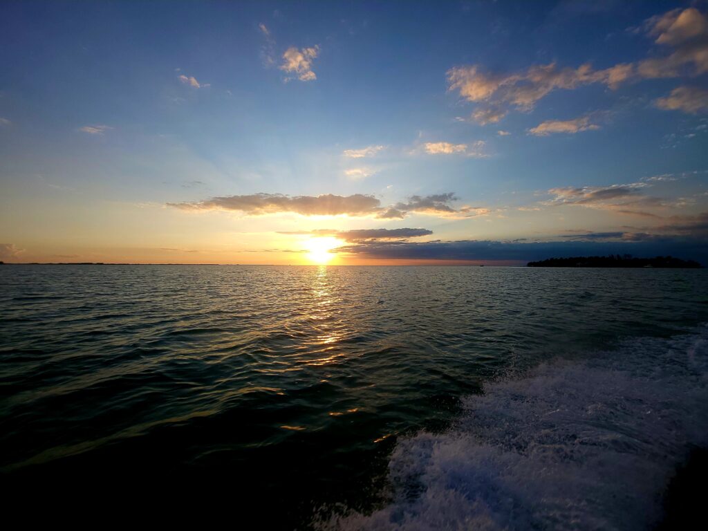 The golden sun setting over the calm Caribbean horizon as seen from the back of the Fish 101 boat."