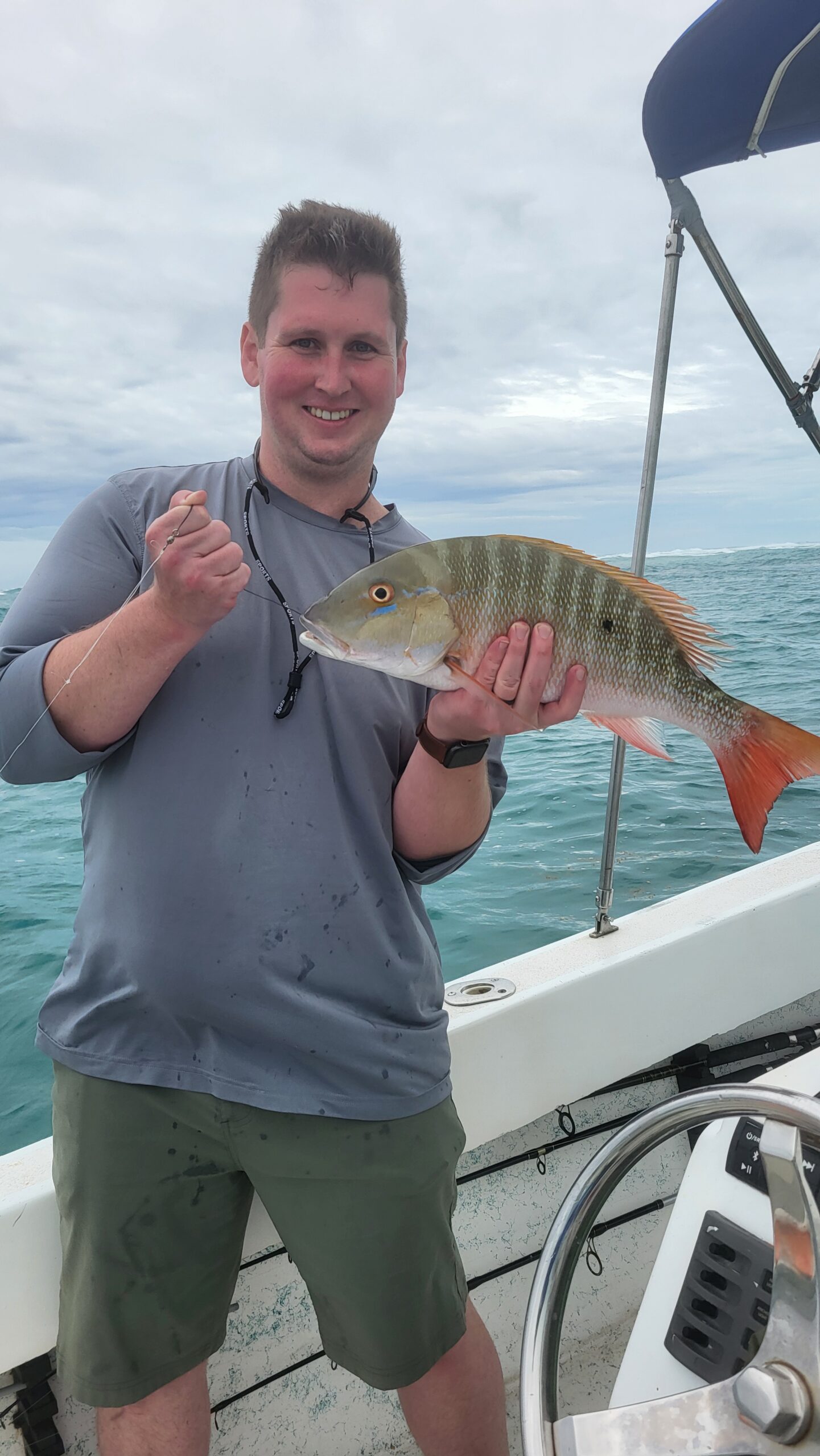 "A happy angler holding a freshly caught Mutton Snapper on a Fish 101 Belize reef fishing charter."