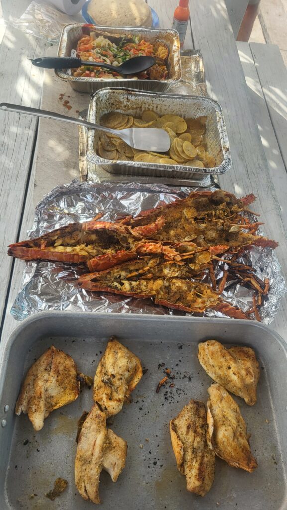 "A spread of freshly grilled lobster tails and seasoned fish fillets ready for an island shore lunch."