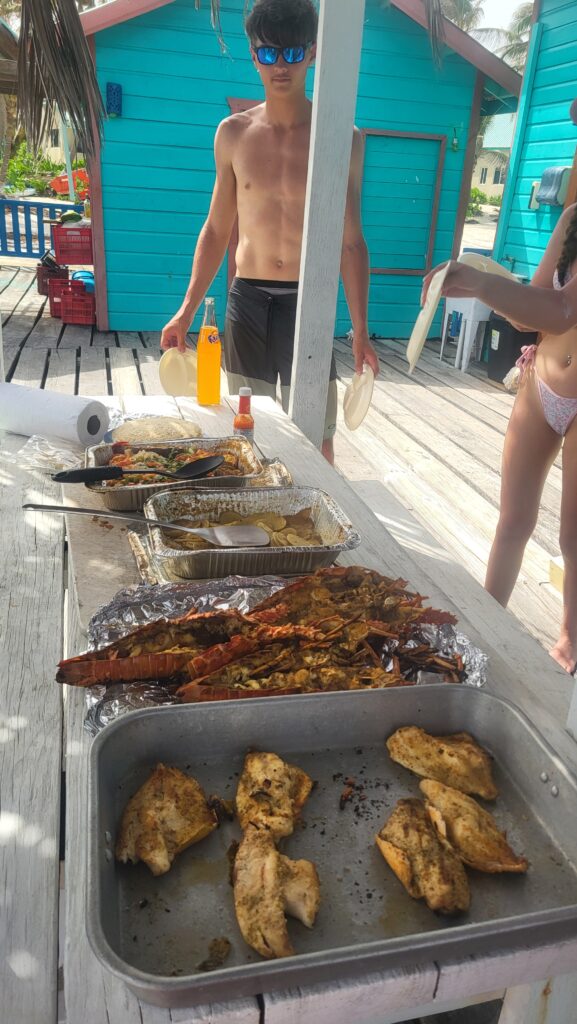 "Guests enjoying a private beach setting with a large spread of freshly cooked seafood on the table."