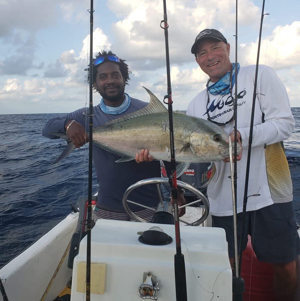 "Two happy anglers holding a trophy-sized Amber Jack caught during a deep-sea fishing trip in Belize."
