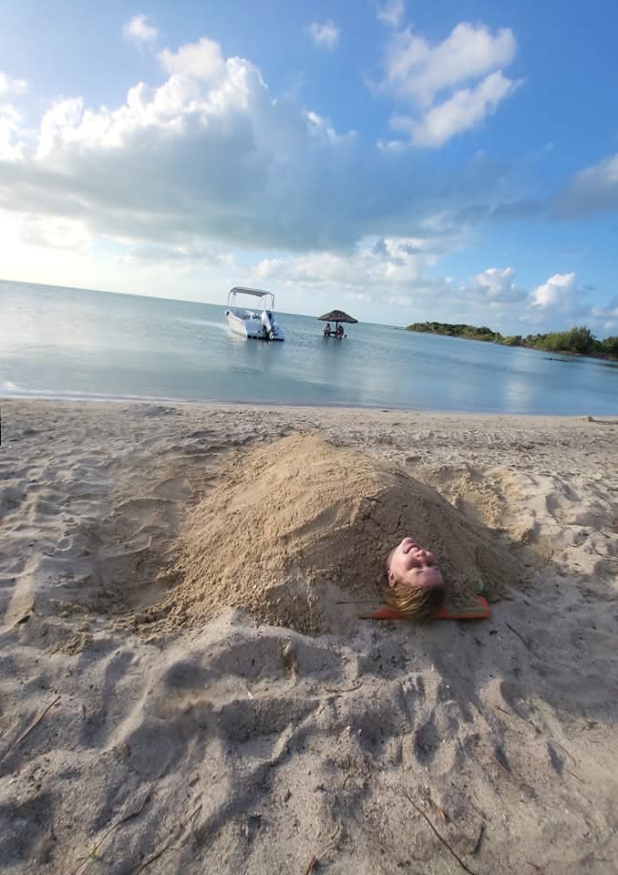 "Fun beach day activity with a guest buried in the soft white sand of a Belizean island."