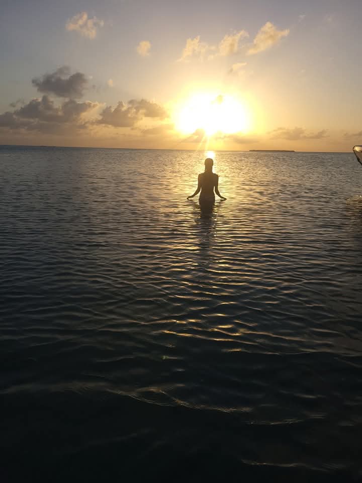 ''Beautiful sunset over the Caribbean Sea in Belize with a silhouette of a person standing in the shallow water.''