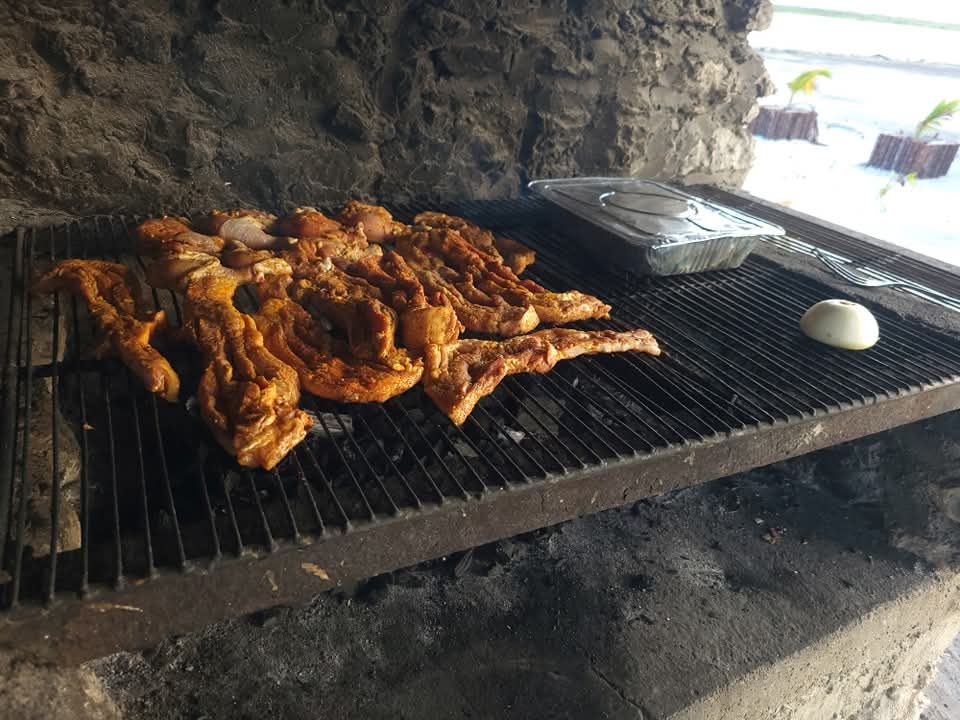 "Delicious barbecue chicken and ribs grilling on a rack alongside scalloped potatoes for a Sunset Beach BBQ experience."