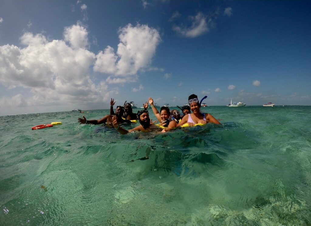 Tourists enjoying a private guided snorkeling adventure and swim in the clear turquoise water of Belize with Fish 101 Belize tours.