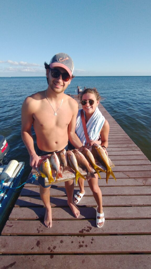 "Tourists holding a string of fresh yellowtail snappers caught on a Fish 101 tour."