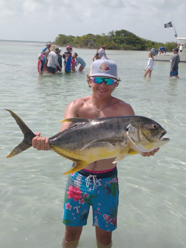 "Smiling angler proudly displaying a large jack cravell.q caught in the Belizean flats."